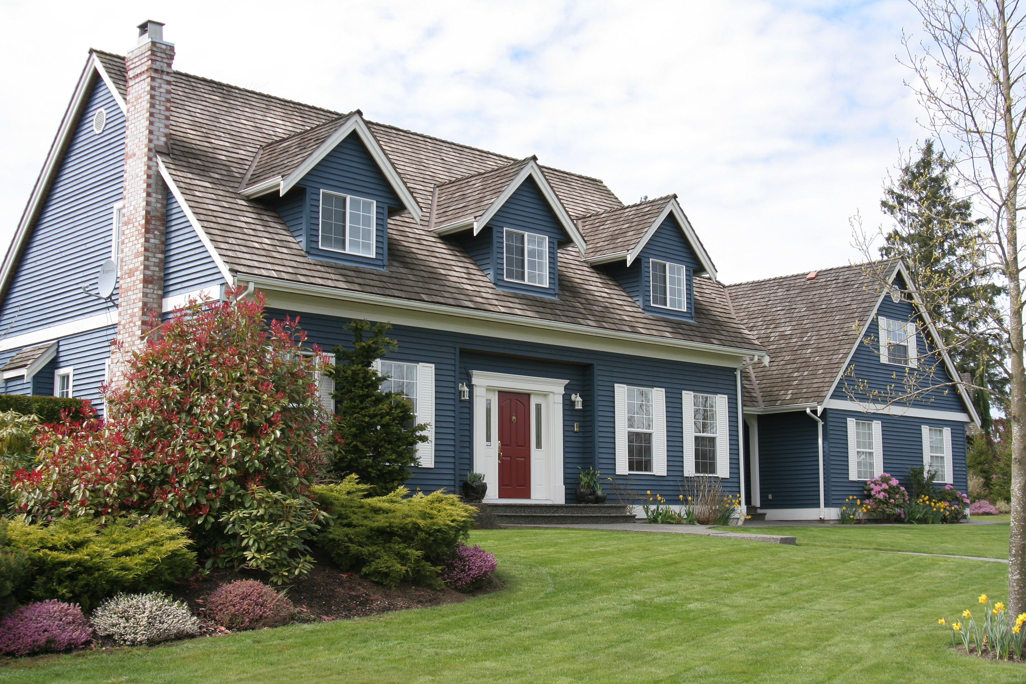 A big house with a lawn and a red door