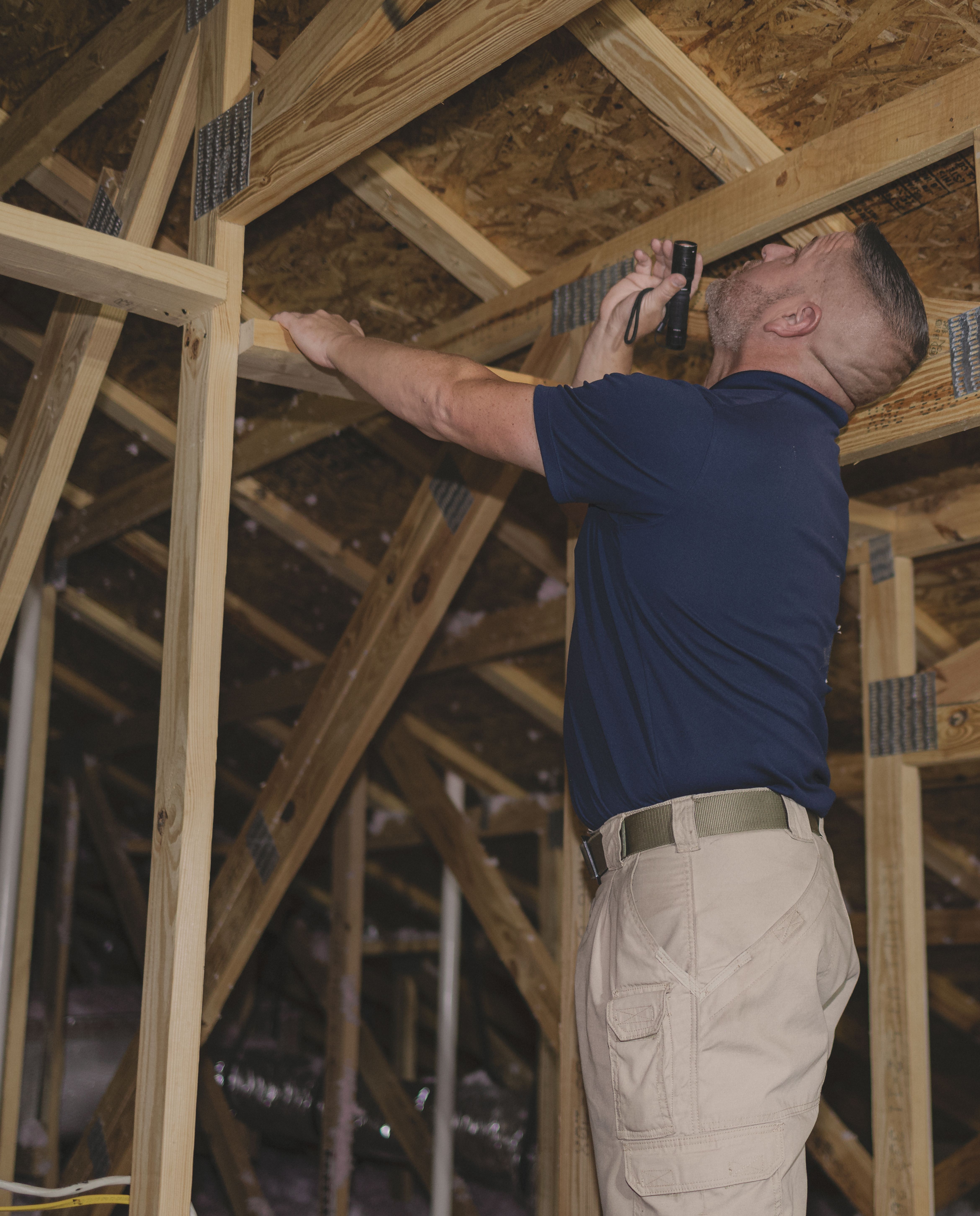 WIN Home Inspector looking at a heat pump outside the house