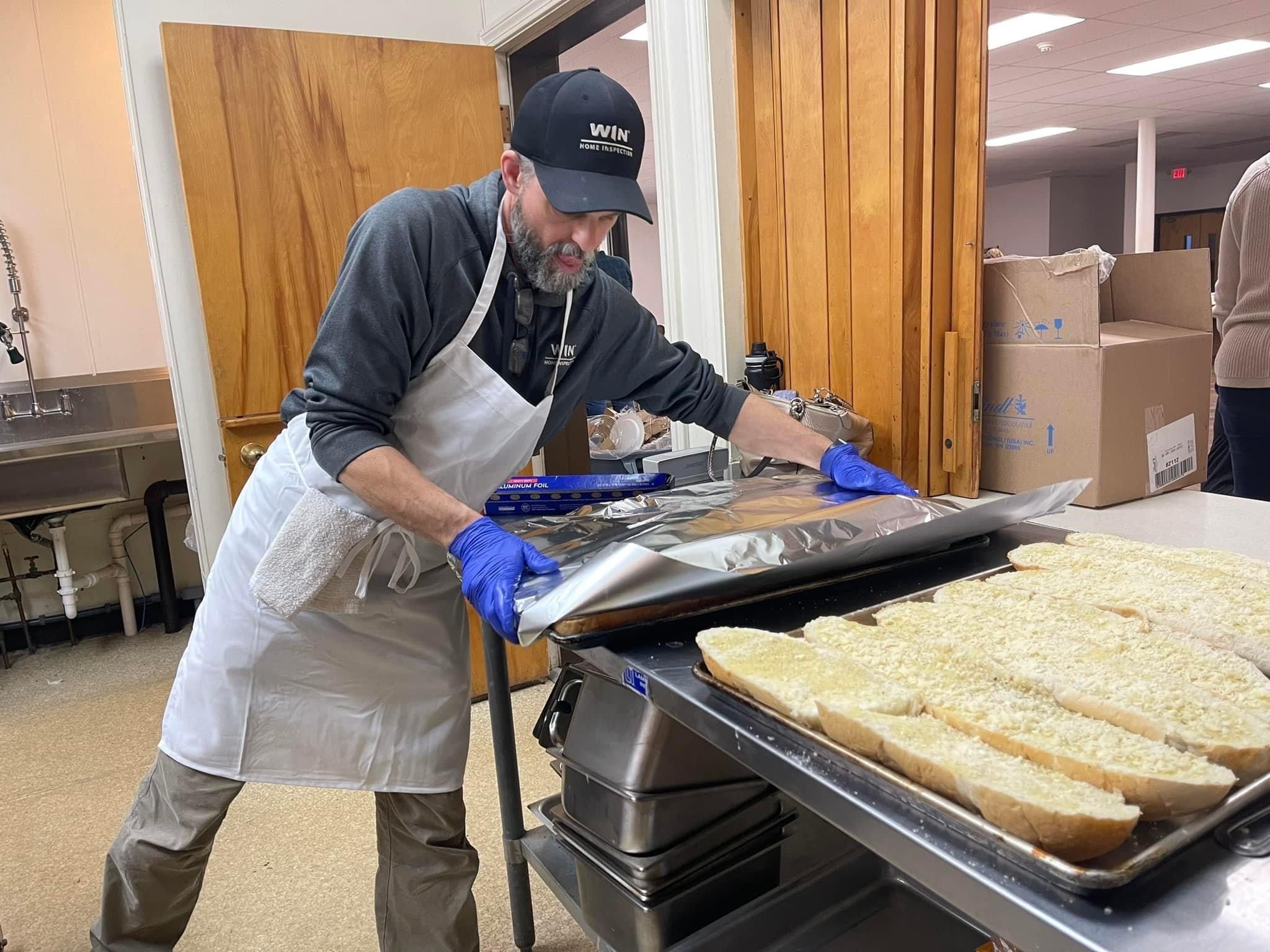 WIN Home inspector in white apron and gloves preparing food.