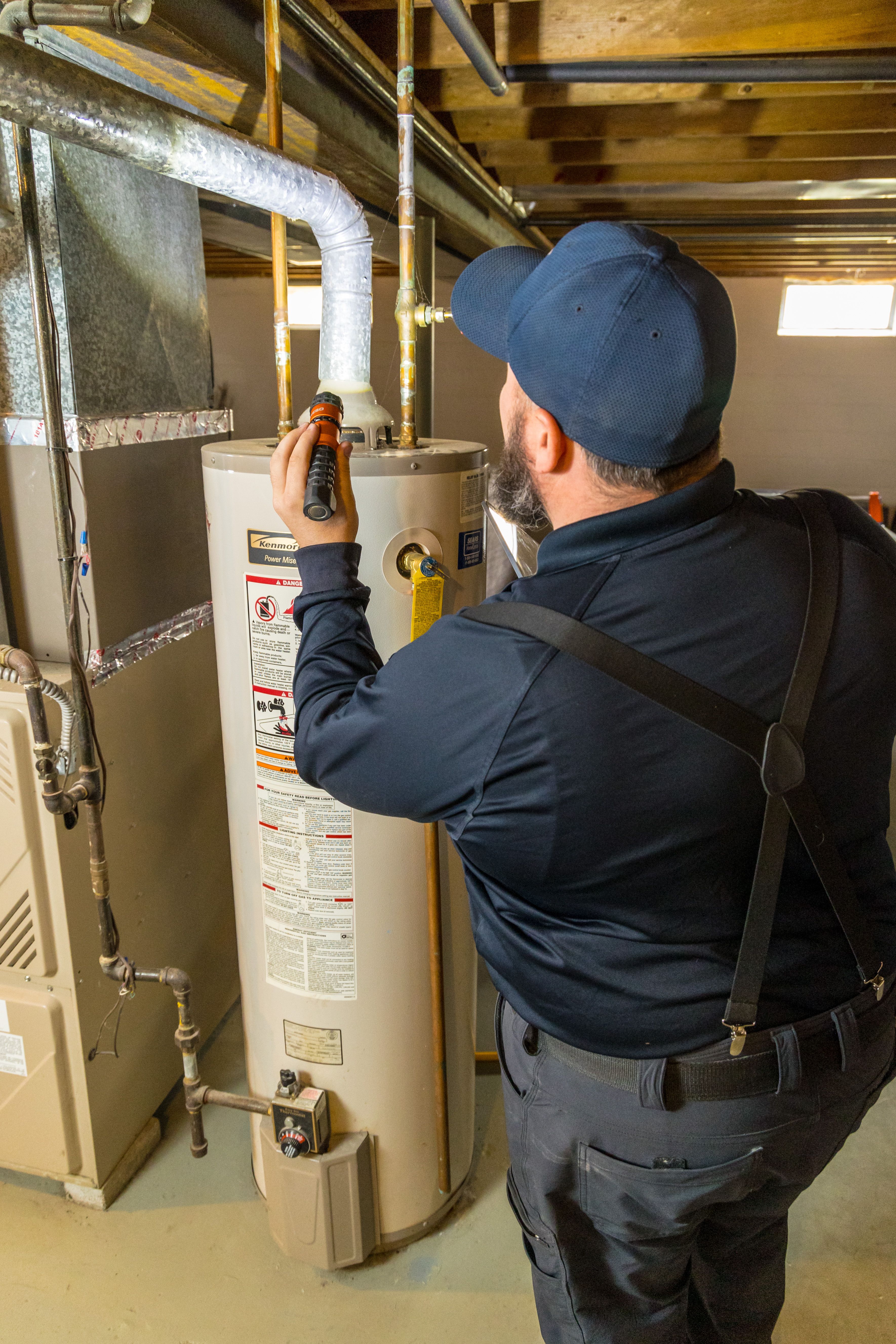 WIN Home Inspector looking at a heat pump outside the house