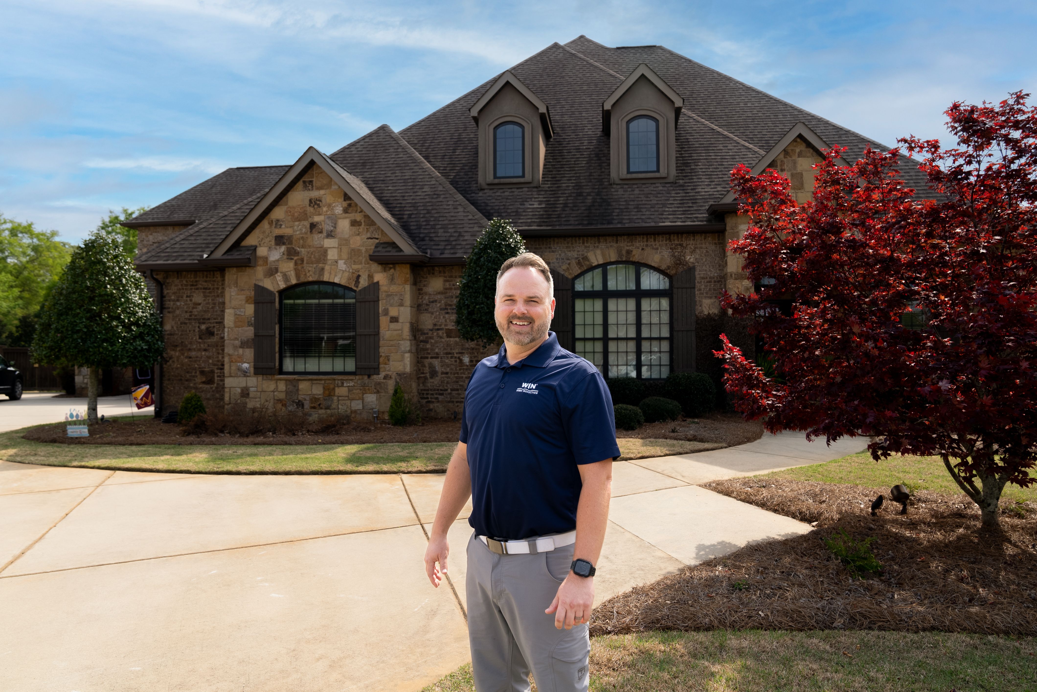 A WIN Home inspector standing in front of a home.