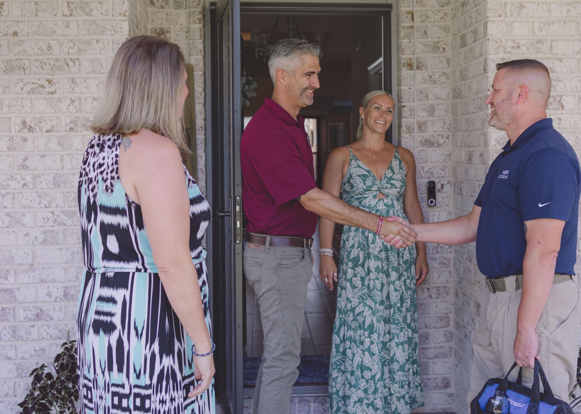 WIN Home Inspector shaking hands with client in front of a house door