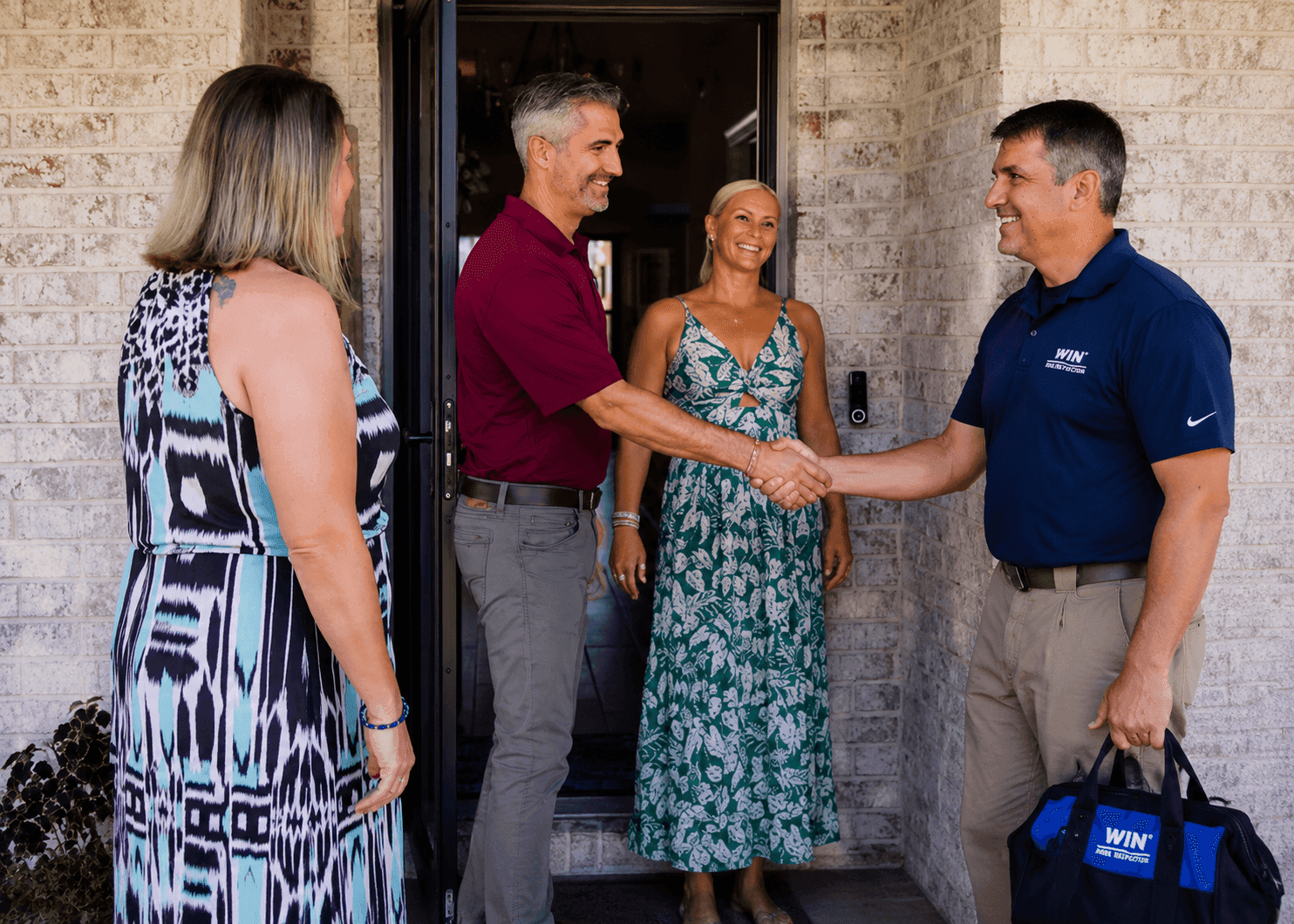 WIN Home Inspector shaking hands with client in front of a house door