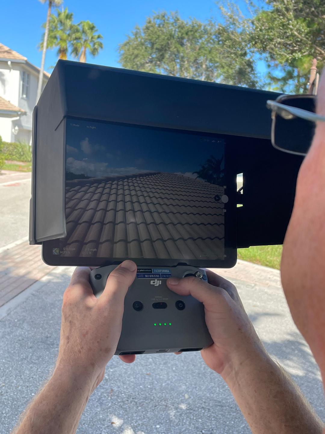 WIN Home inspector using a drone controller to inspect a roof.