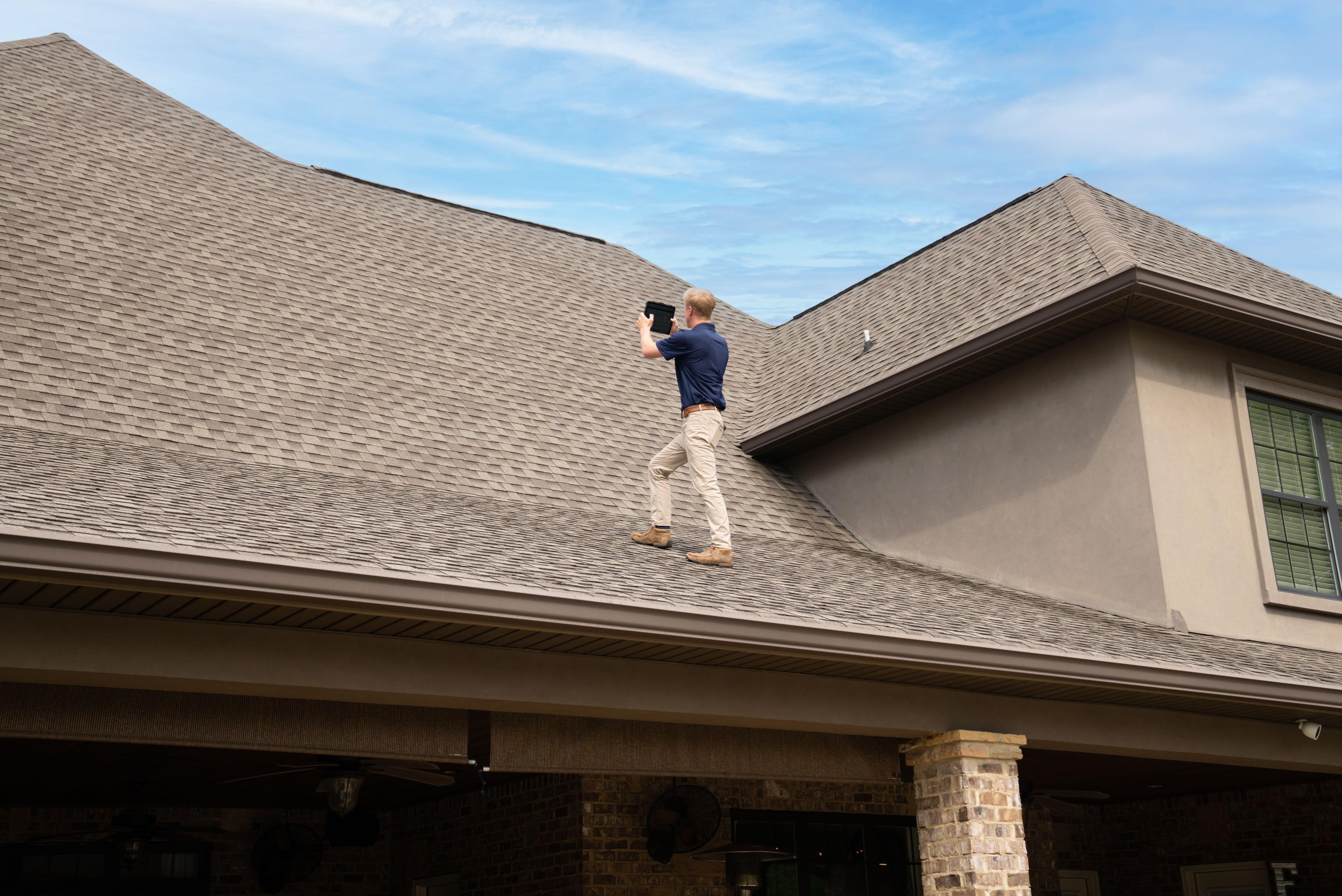 Home Inspector inspecting the roof of a house using a tablet device