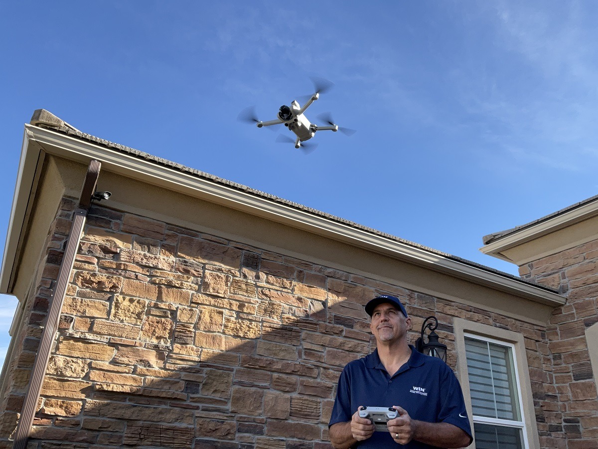 Home Inspector flying drone over house roof for inspection