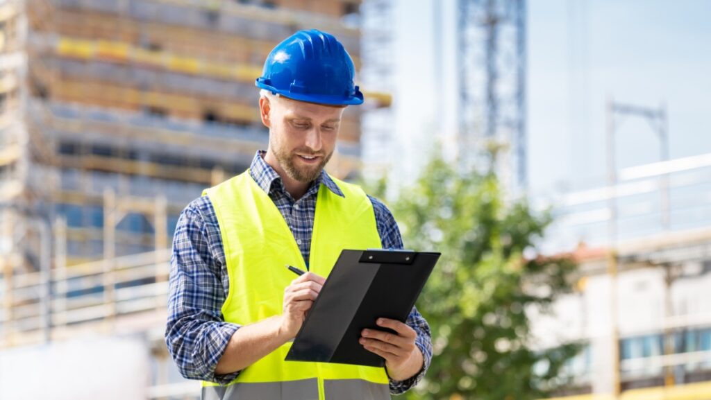 Building inspector with a hat and clipboard at a construction site