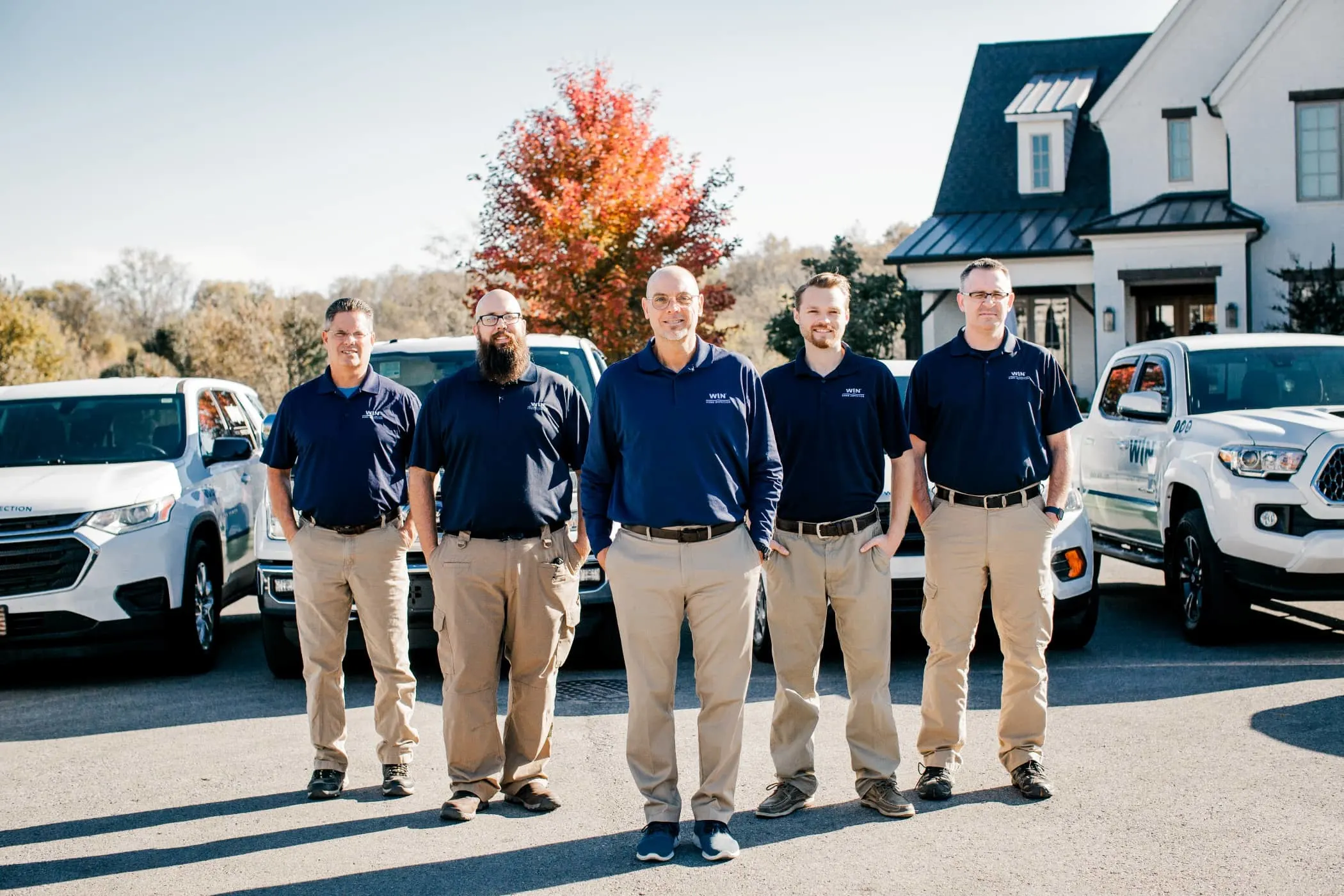 WIN Home Inspectors group posing in front of WIN vehicles