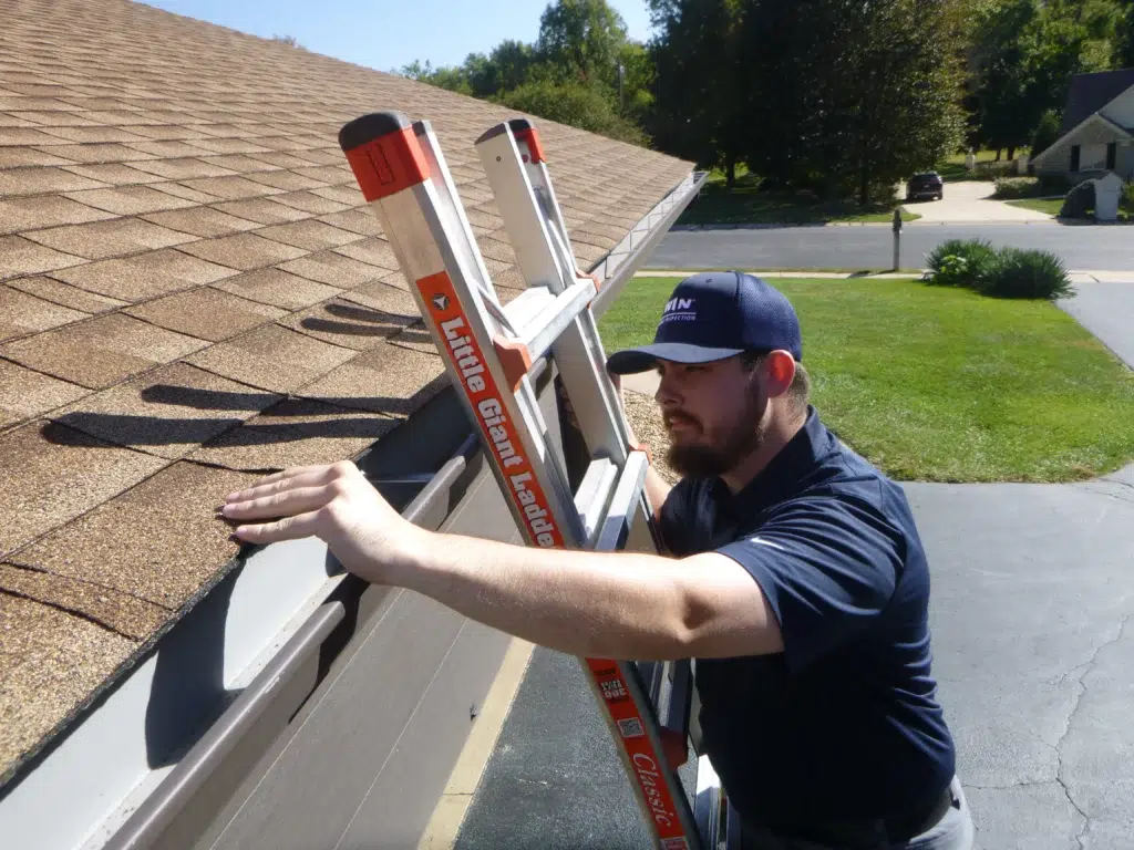 home inspector checking house roof on a ladder